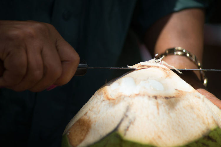 Close-up of man opens a coconut