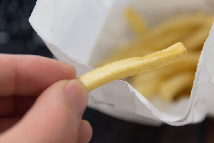 Cropped image of hand holding french fry