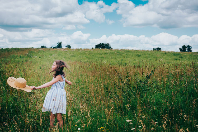 Girl in wildflower field against blue summer sky