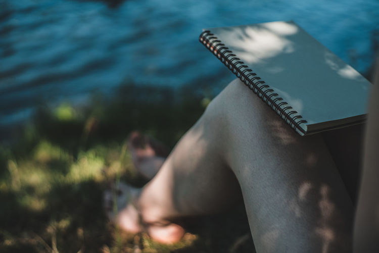 Low section of woman with diary sitting at beach