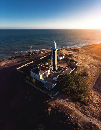Aerial view of the lighthouse and adjacent technical buildings on the seashore at sunset