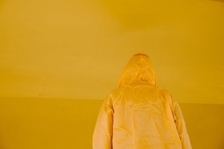 Low section of woman standing against yellow wall