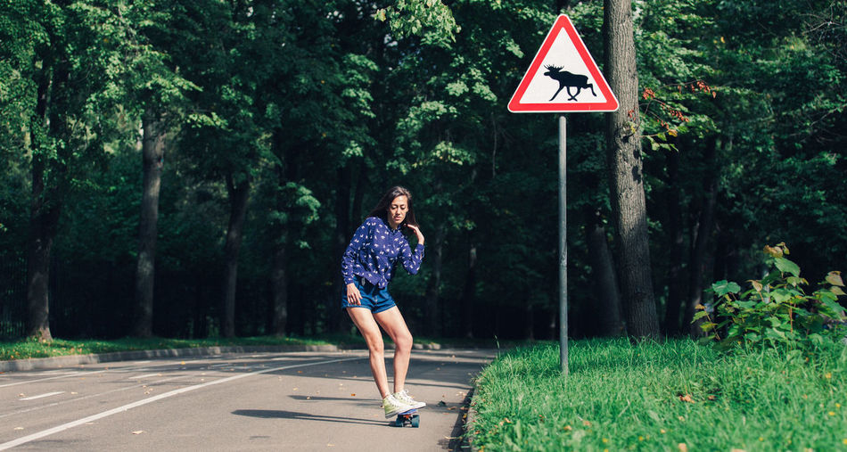 Full length of woman skateboarding on road