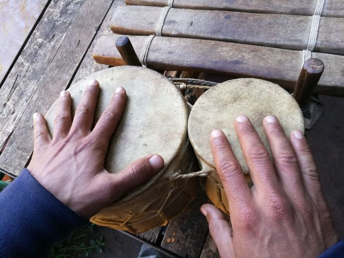 Cropped hands of man playing drums on wooden table
