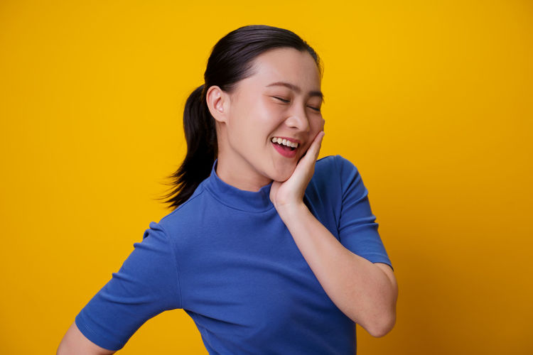 Smiling young woman against yellow background