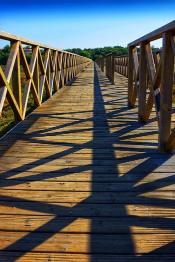 Wooden footbridge on footpath against sky