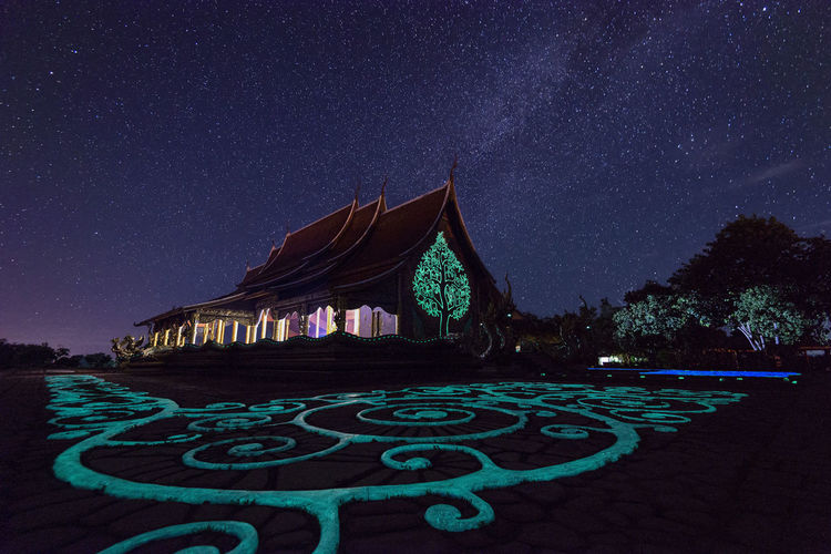 Low angle view of illuminated temple against star field at night