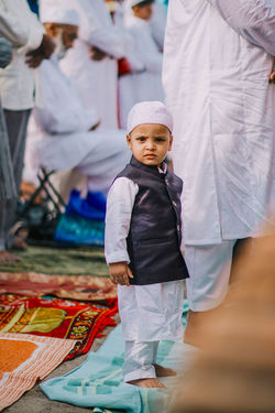Portrait of cute boy in traditional clothing standing on mat