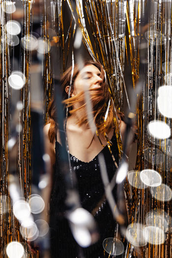 Woman dancing on new year party, shiny curtain decor and blurred lights