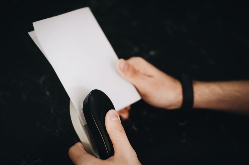 Midsection of person holding paper against black background