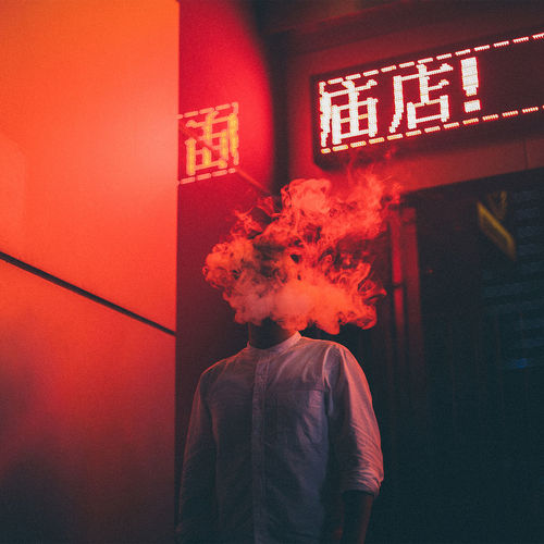 Man smoking against illuminated wall at night