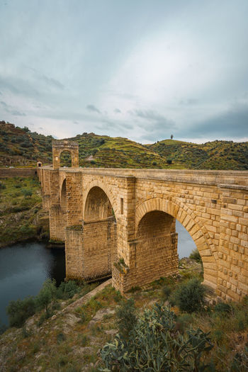 Arch bridge over river against sky