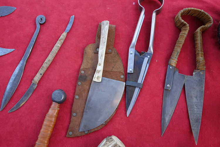 High angle view of various daggers on red fabric