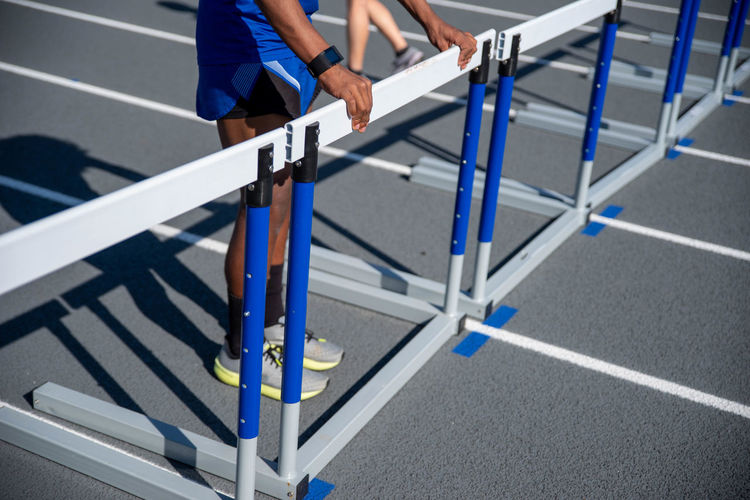 Young man positions hurdles lined up on running track