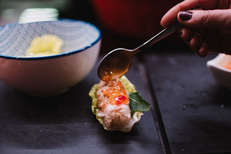 Closeup anonymous female smearing spoonful of sauce on exquisite dish during cooking course in restaurant in navarre, spain