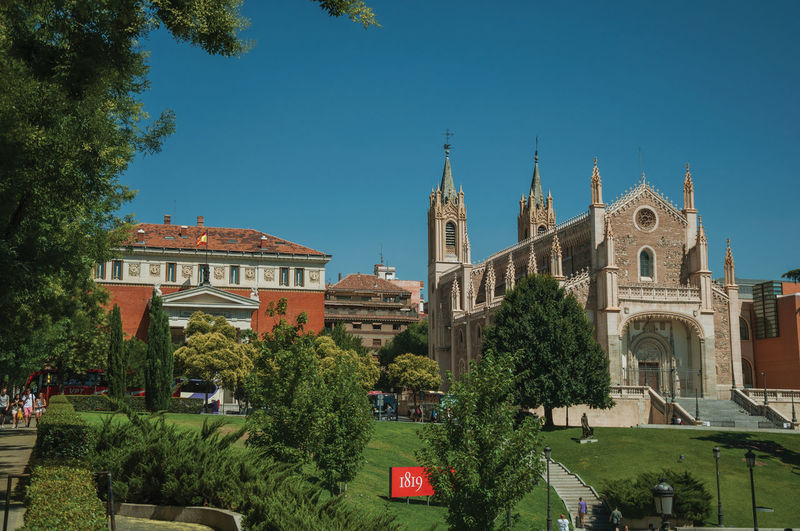 People on garden with trees in front of the san jeronimo el real cathedral in madrid, spain.