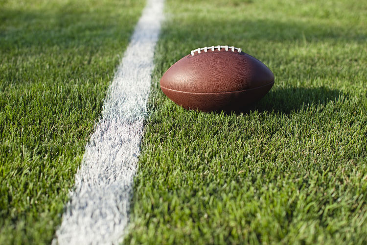 American football ball close to white line on playing field