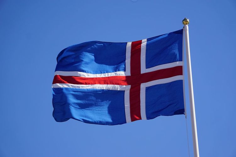 Low angle view of icelandic flag against clear blue sky