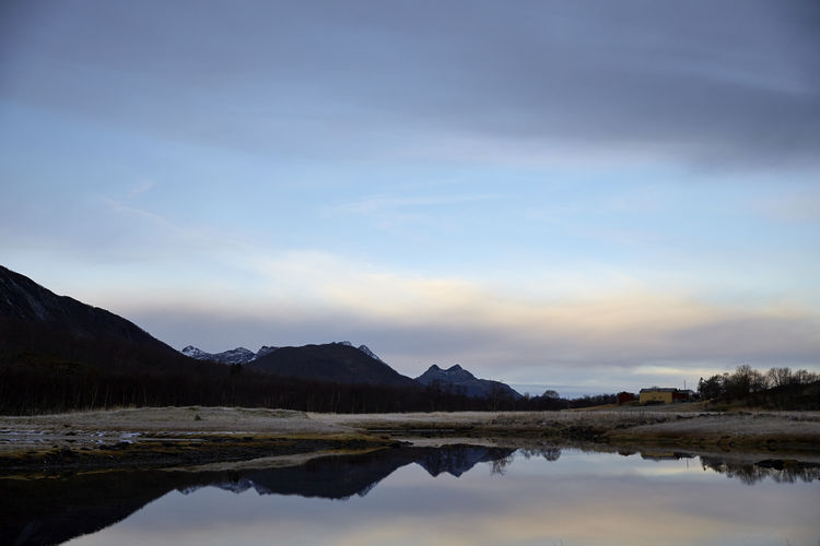 Scenic view of lake by mountain against sky