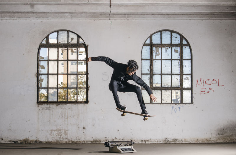 Full length of man skateboarding against windows