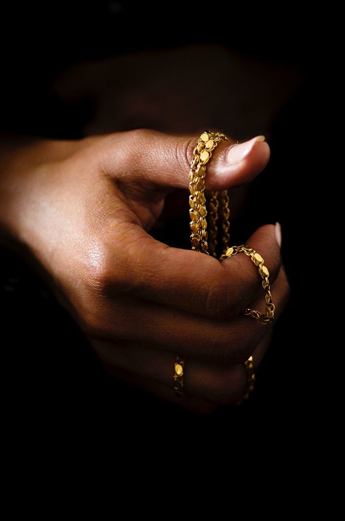 Close-up of cropped hand holding gold necklace
