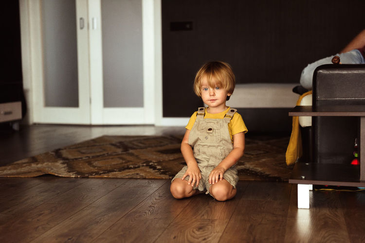 Little boy sitting on the carpet in the house