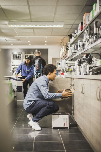 Salesman keeping appliance in shelf while working at electronic store