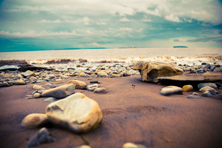 Rocks on shore at beach against sky