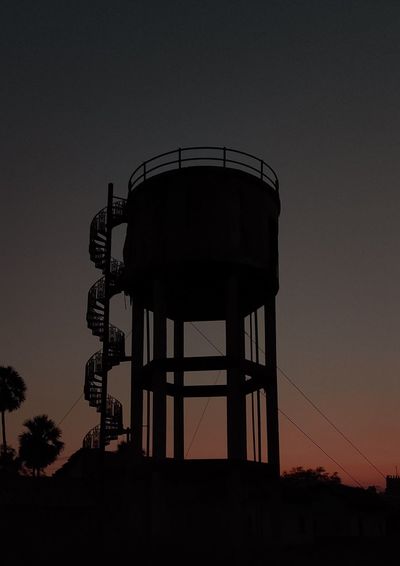 Low angle view of water tower against sky at sunset