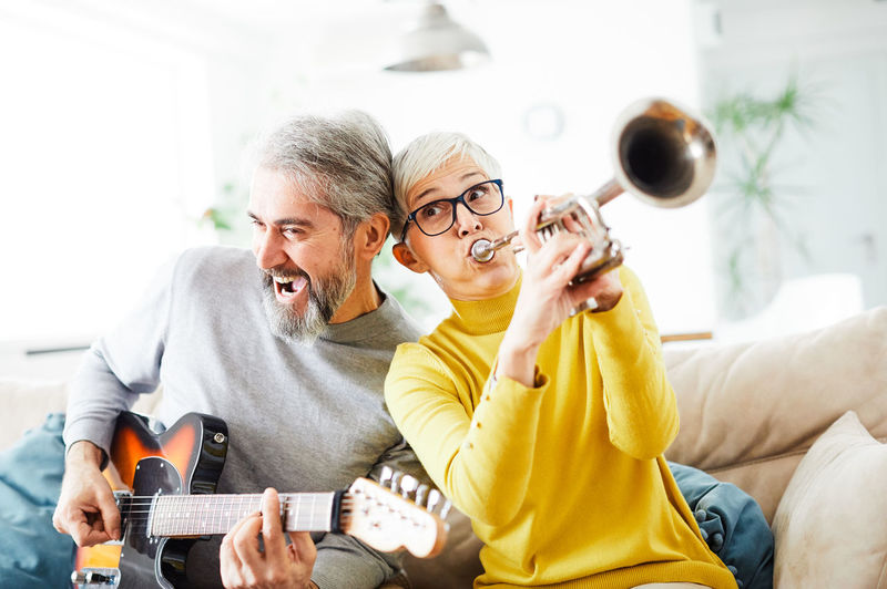 Senior couple playing music instruments at home