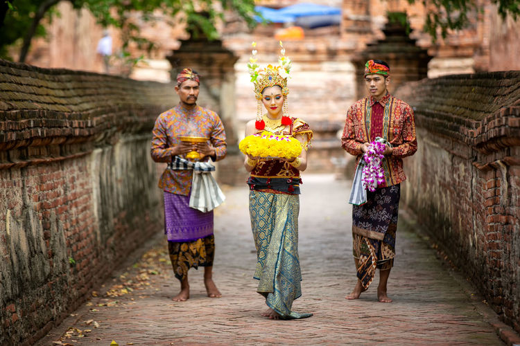 Men and woman with religious offerings walking on footpath