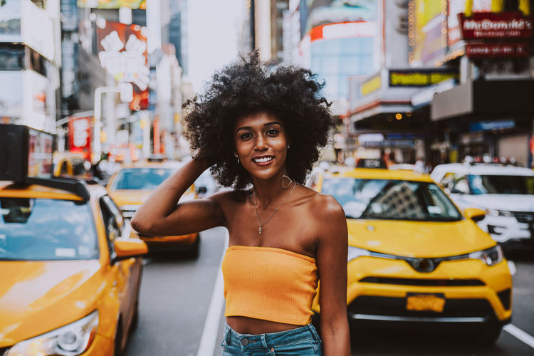 Portrait of confident young woman with afro hairstyle standing on city street
