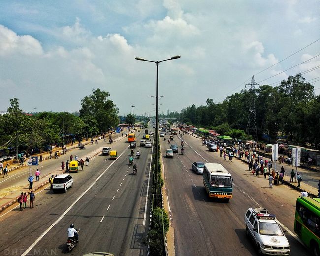 High angle view of people and vehicles on road against sky