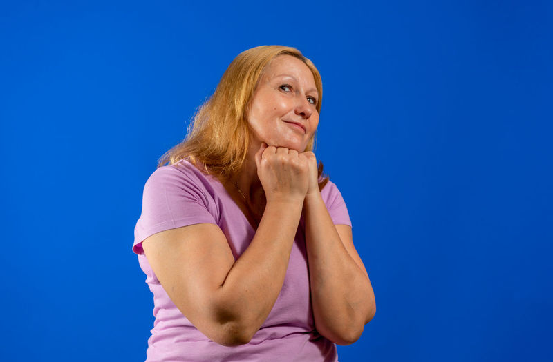 Mid adult woman looking away against blue background