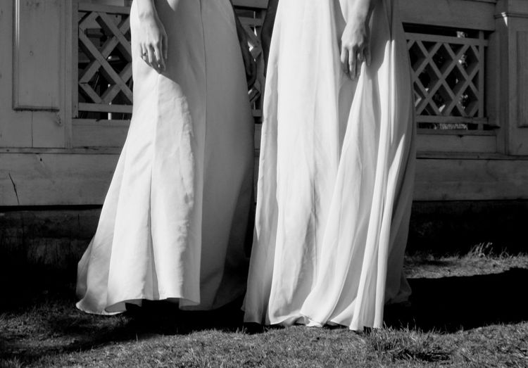 Low section of lesbian couple during wedding ceremony standing against on field