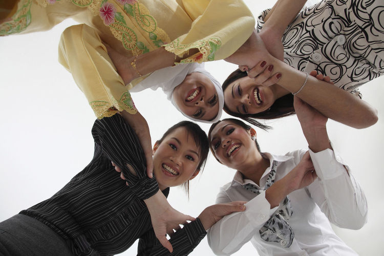 Low angle view of female friends huddling against white background