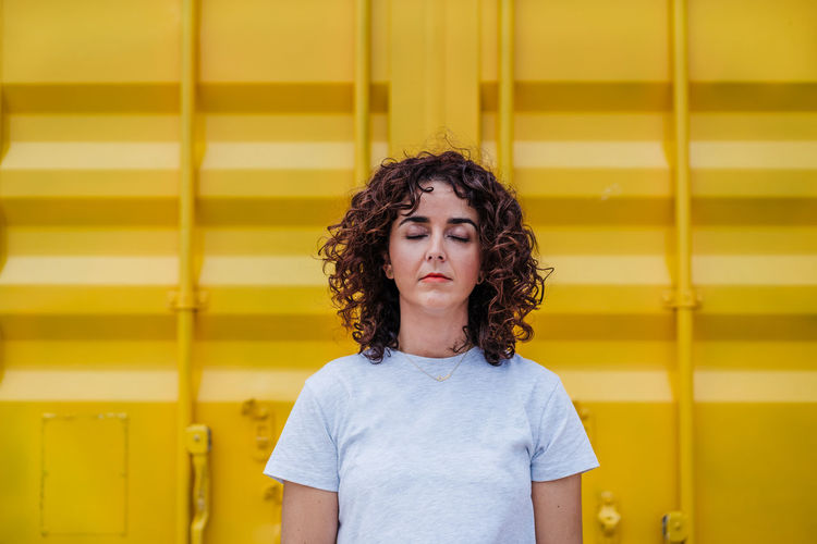 Portrait of teenage girl standing against yellow wall