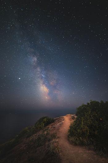 Night landscape path on the hill goes towards the milky way over the night sea