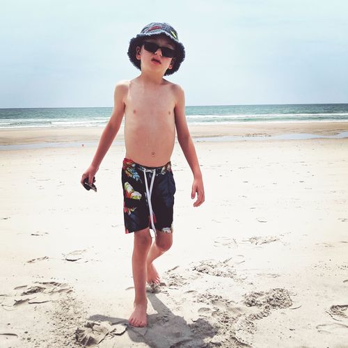 Full length of shirtless boy walking at beach