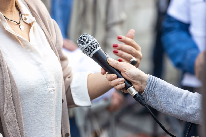 Midsection of woman holding microphone