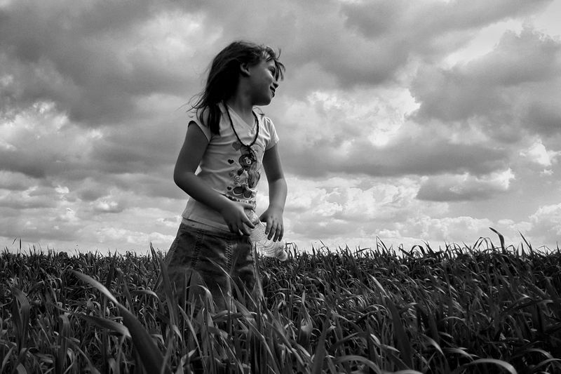 Girl standing in wheat field against sky