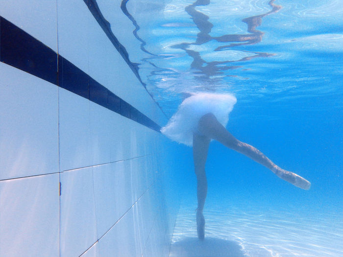 Low section of ballerina practicing in swimming pool