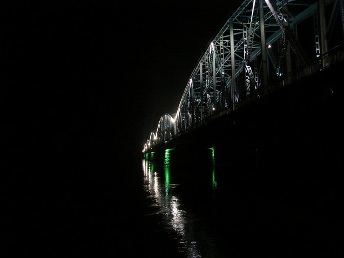 Low angle view of illuminated bridge over sea against sky at night