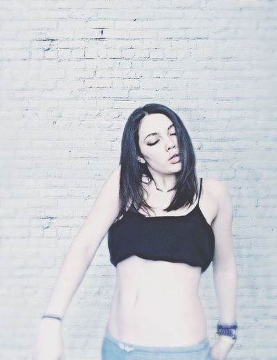 Portrait of young woman standing against wall