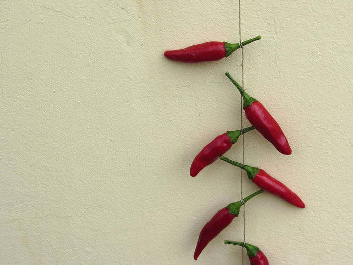 Close-up of red chili peppers on table against wall