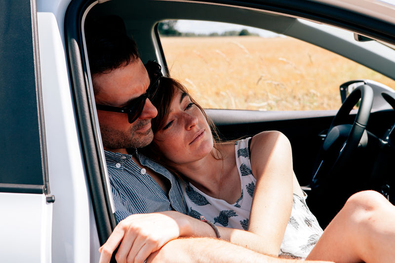 Couple sitting in a parked car on a warm daylight relaxing and bonding together