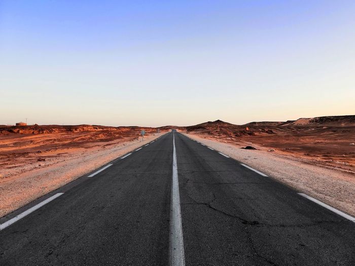 Diminishing perspective of empty road at desert against clear sky