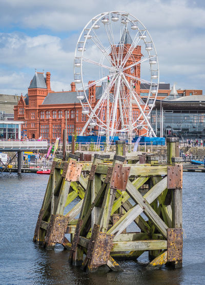 Ferries wheel on wooden pier against cloudy sky