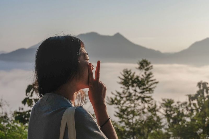 Woman gesturing against mountains during foggy weather