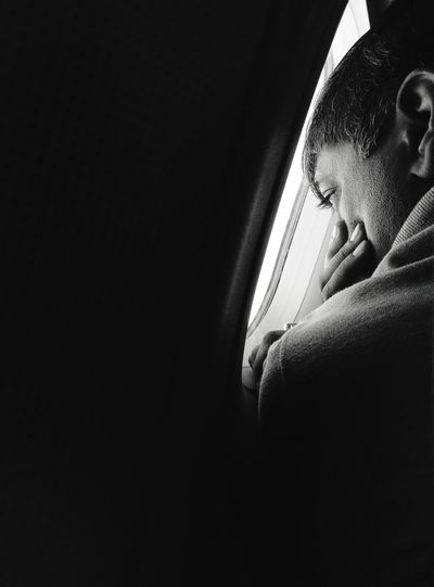 Close-up of man looking through window of airplane